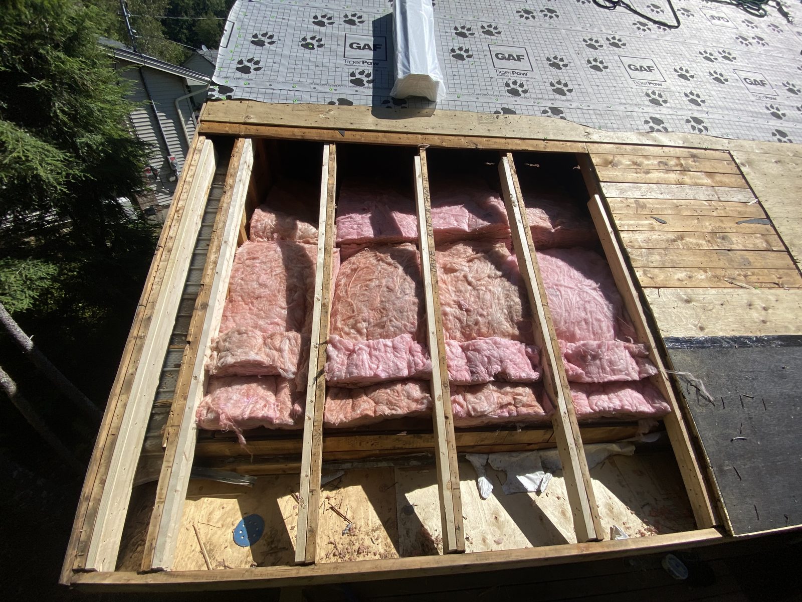Roof opened up showing rafters and insulation with new underlayment beyond
